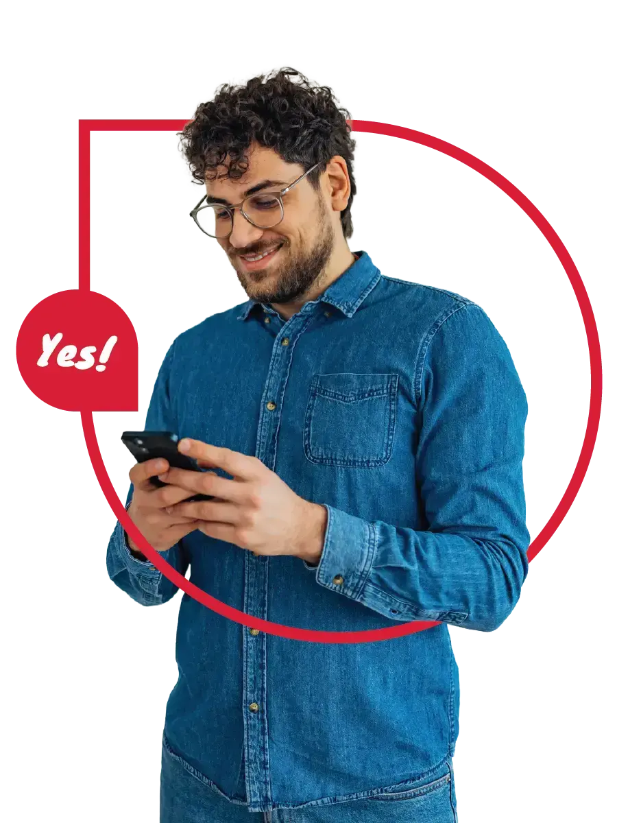 A man in a blue shirt looks at his smartphone and smiles. 